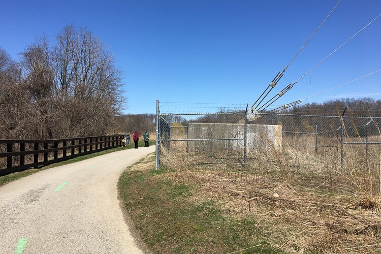Walkers amble by one of the tower's substantial guy wire tether.