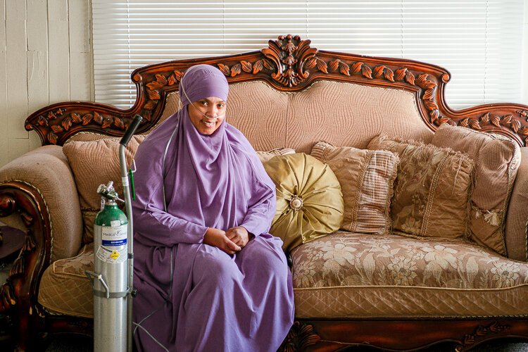 Rashidah Abdulhaqq at her home that was built nearly a century ago, and it’s drafty, driving up her utility bills on top of the costr to run the oxygen tank she needs.