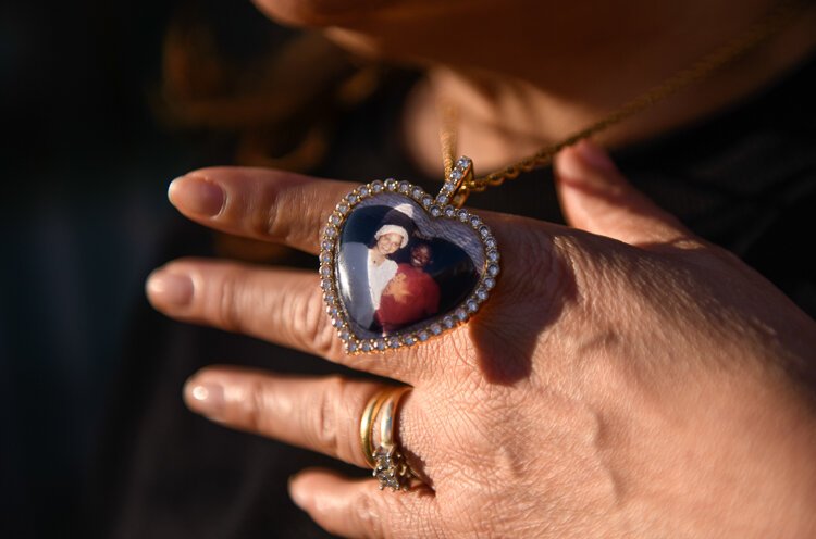 Kevina Chapolini holds up a necklace with a photo of herself and her husband who died last year following a battle with cancer, from which Chapolini is also a survivor.
