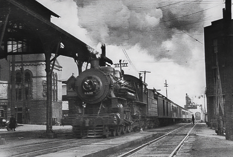 Train going by the Terminal & Valley Railway depot building (left)
