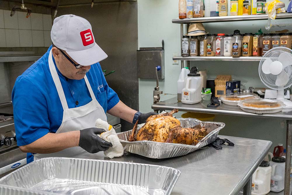 Catholic Charities distributes more than 12,000 free Thanksgiving meals every year to community members in need. Here, a volunteer carves turkeys at St. Augustine Hunger Center.