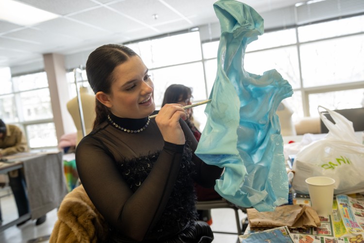 A KSU fashion design student paints a piece of fabric before adding it to a Salvador Dali-inspired garment.