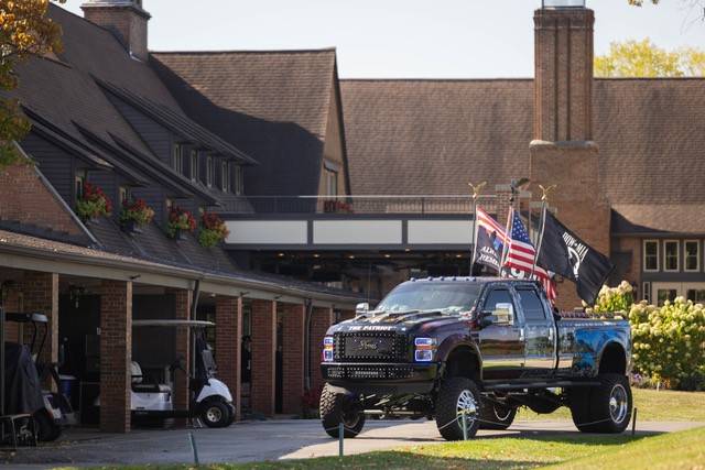 A truck flanked with the American Flag, a POW/MIA Flag, and a First Responders Flag.