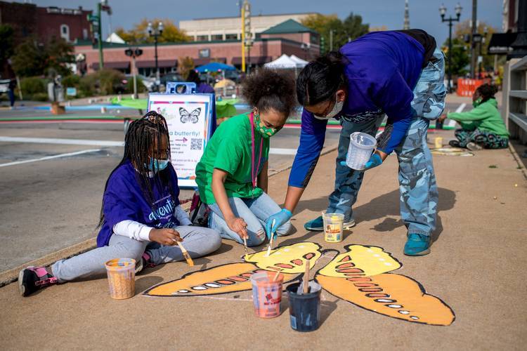 People paint butterflies along Court Street during the Great Mural Project Asphalt Mural Paint-A-Thon on Sept. 26, 2020 in Saginaw, Michigan. (Photo by Nic Antaya/Bloomberg Philanthropy)