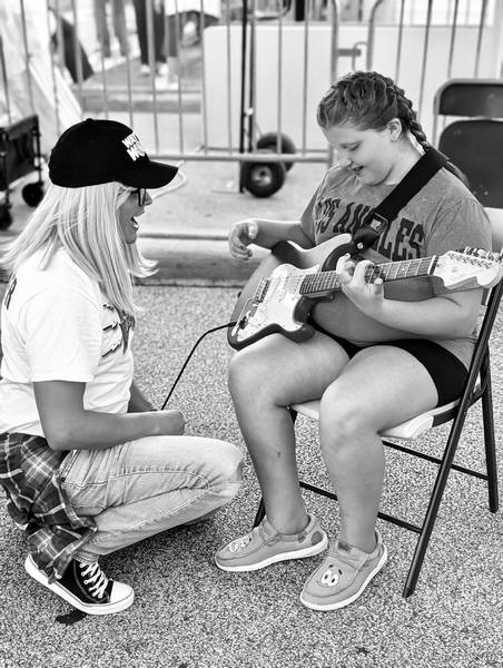 A young woman gets a guitar lesson at Rock the Block 2026.