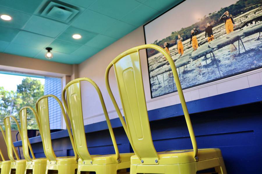 Yellow chairs line the bar, facing a French painting of oyster farmers.