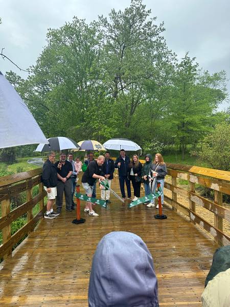 Derek Schafer of West Creek Conservancy helps cut the ribbon marking the opening of the West Creek Greenway.