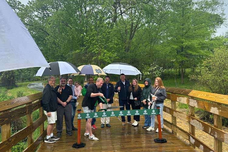 Derek Schafer of West Creek Conservancy helps cut the ribbon marking the opening of the West Creek Greenway.
