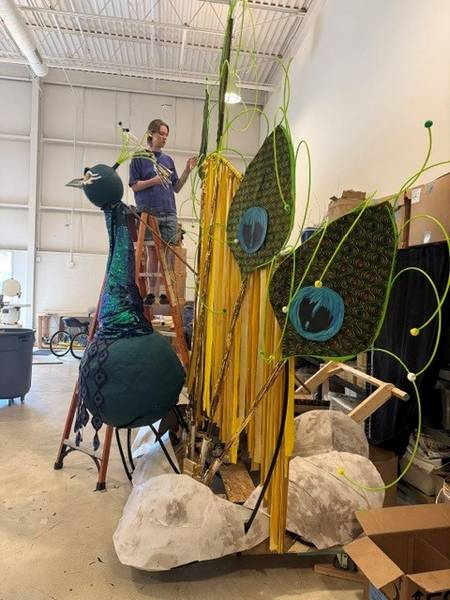 A volunteer builds a giant peacock for Parade the Circle.