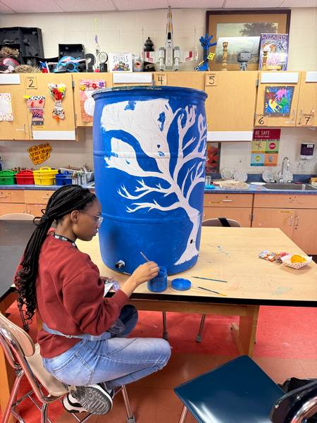 A Willson School student finishes painting a rain barrel.