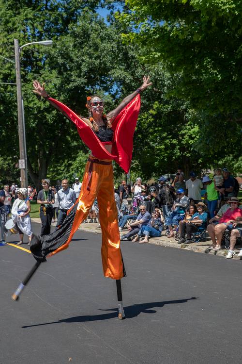 A stilt walker parades down the street.