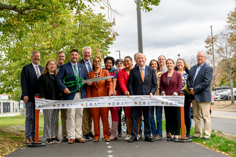 A group gathers at the entrance to the Mandel Community Trail before the ribbon cutting.