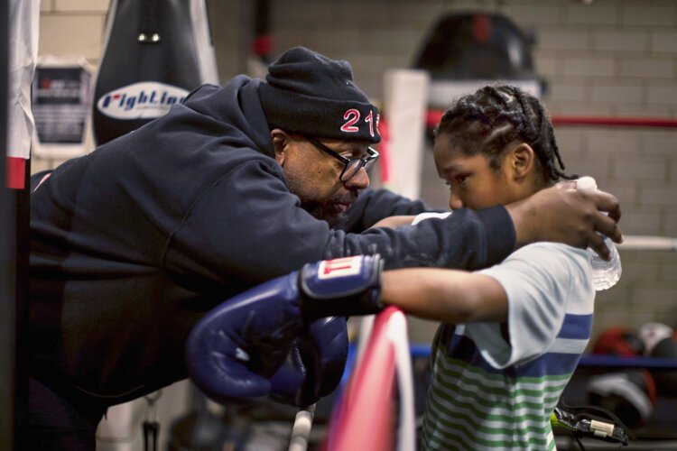 Coach Fred consoles a young boxer after his first sparring match.