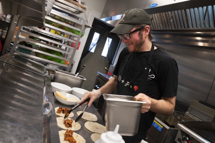 Joshua Sias preparing tacos in the kitchen at Foodhisattva.