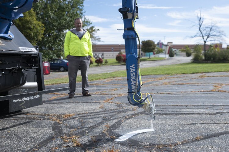 Robotics expert Wyatt Newman watches as the robotic arm sprays a test arrow.