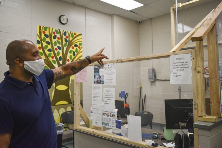 David Blunt, shows how the shelter has set-up a plexiglass barrier at its entryway to protect residents and staff during the pandemic.