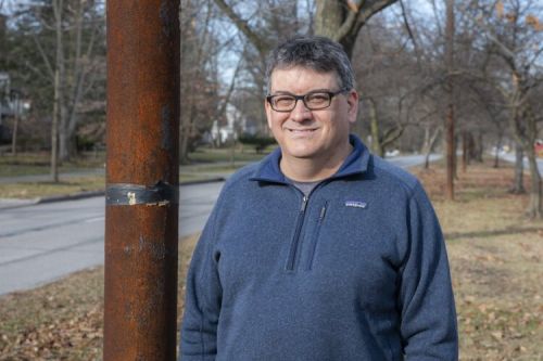 Brad Masi poses next to one of the old streetcar poles still standing on Fairmount Boulevard in Cleveland Heights.