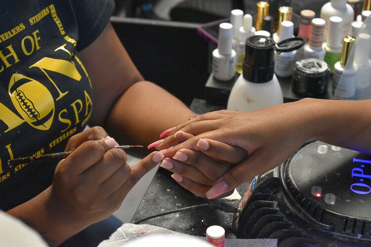 Rain Burnside, owner of A Touch of Rain Nail Spa in Larchmere,  provides a manicure to a client during a November event meant to educate people on the Child Tax Credit.