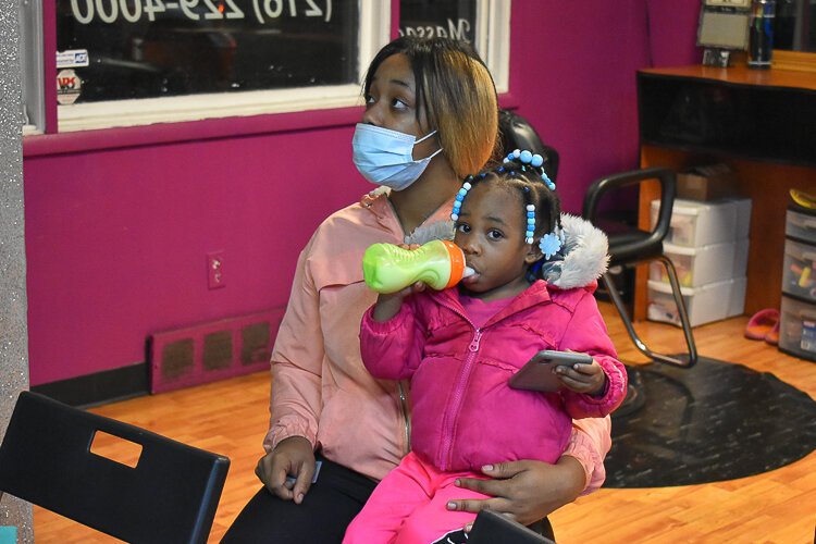 Kayla Minor, a local home health aide, sits with her two-year-old daughter A’Riyah as she learns about the Child Tax Credit during a November event at A Touch of Rain Nail Spa in Larchmere.