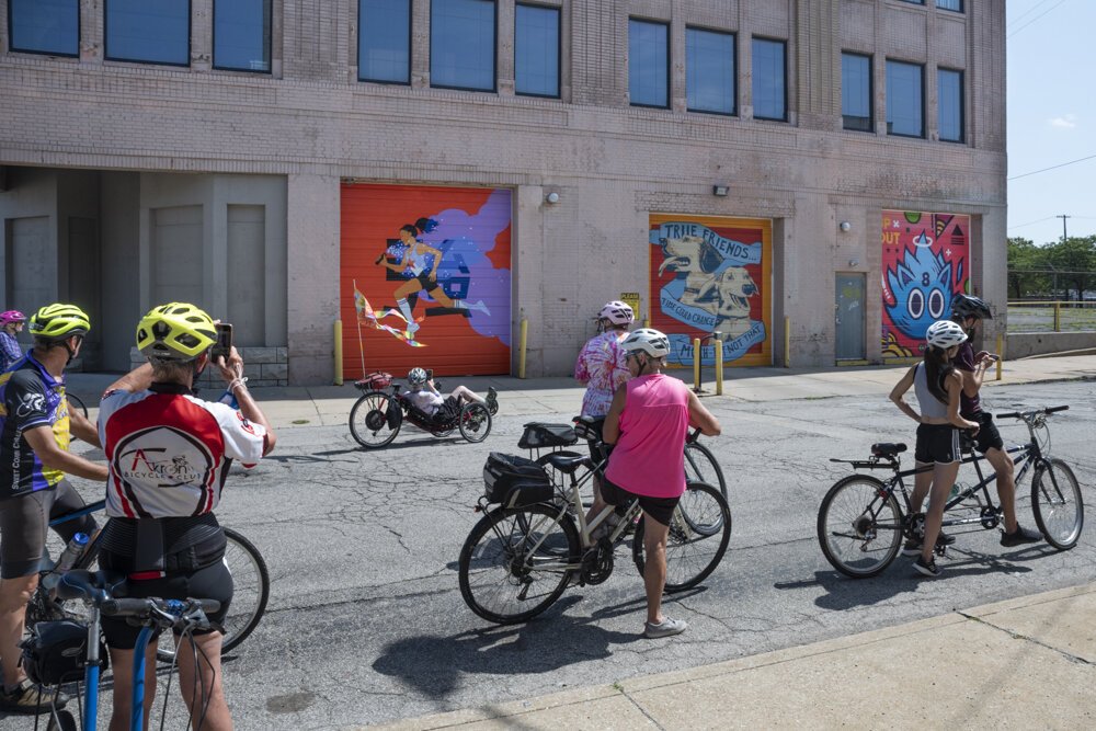 Bicyclists checking out the murals (L-R) by artist Julia Kuo, April Bleakney and Jordan Wong &Chad Fedorovich at 4600 Euclid Avenue.