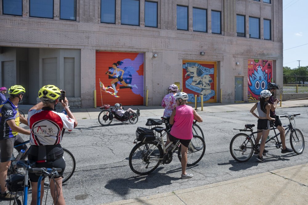 Bicyclists checking out the murals (L-R) by artist Julia Kuo, April Bleakney and Jordan Wong &Chad Fedorovich at 4600 Euclid Avenue. 