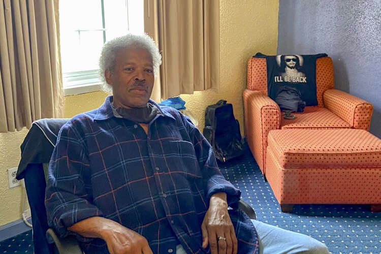 Abel Currie, 63, sits in his hotel room in May. It’s been a relief for him to have space to quarantine safely as he searches for a permanent apartment.