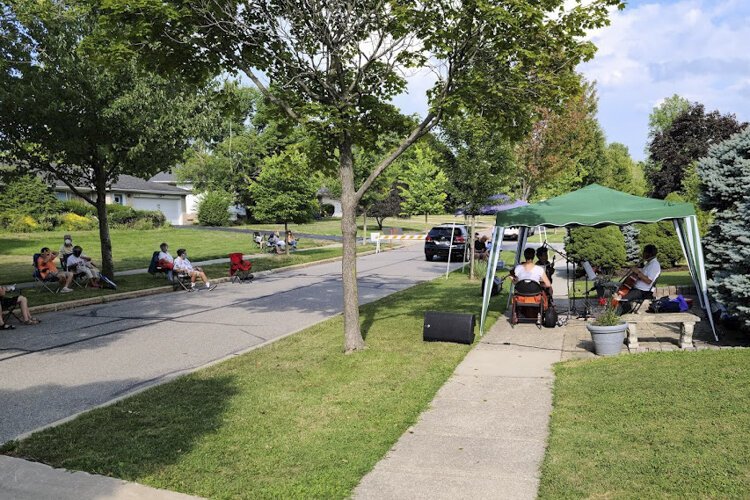 Musicians set up on George Carr’s front lawn as spectators watch from across the street.