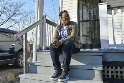 Denesha Moses sits on her porch in the Buckeye-Woodhill neighborhood. Moses received help from the Cleveland right to counsel program last year after her former landlord filed an eviction against her. 