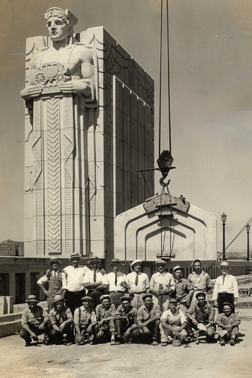 Masons who worked on the "Guardians of Transportation" pose in front of one of their creations as it is being installed.