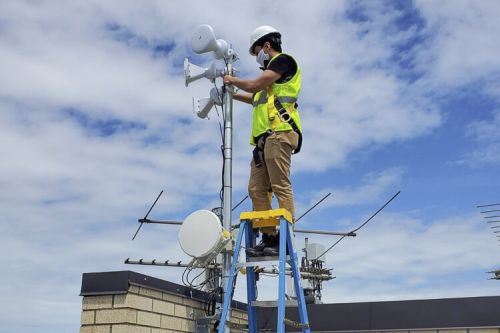 Rolando Alvarez installing radios atop Cuyahoga Metropolitan Housing Authority’s Scranton Castle building in Cleveland’s Clark-Fulton neighborhood.