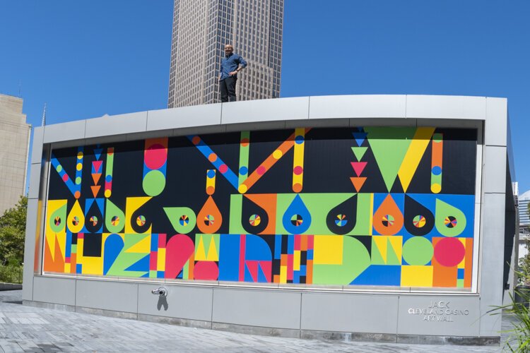Artist Leandro Castelao stands atop his café art wall mural in Public Square sponsored by LAND studio.